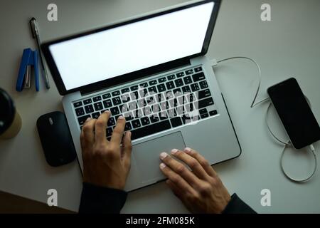 Lange Arbeitszeiten. Draufsicht auf den Arbeitsplatz eines jungen Mannes, der am Laptop arbeitete und spät in der Nacht am Tisch im dunklen Zimmer saß Stockfoto