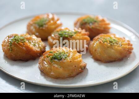 Türkisches und arabisches traditionelles Ramadan Dessert Lor Käse Dessert mit Pistazien-Pulver und Sirup Servieren auf dem Teller. Stockfoto