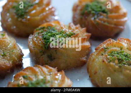 Türkisches und arabisches traditionelles Ramadan Dessert Lor Käse Dessert mit Pistazien-Pulver und Sirup Servieren auf dem Teller. Stockfoto