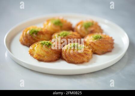 Türkisches und arabisches traditionelles Ramadan Dessert Lor Käse Dessert mit Pistazien-Pulver und Sirup Servieren auf dem Teller. Stockfoto