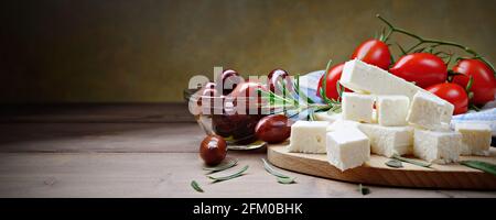 Feta-Käse mit kalamata-Oliven, Tomaten und Rosmarin auf Holztisch, Nahaufnahme, Platz für Text. Stockfoto