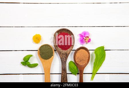 Viele Holzlöffel mit Superfood-Pulver in einer Reihe auf weißem, minimalem Holzbrett-Hintergrund mit viel Platz zum Kopieren. Stockfoto