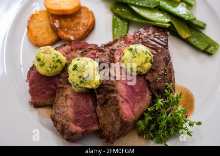 Entrecote mit Kräuterbutter und Kresse, Pomme Souffle Potatos und grünen Bohnen Stockfoto