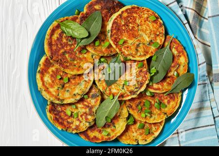 Kichererbsen-Spinat-Pfannkuchen auf einem blauen Teller auf einem weißen Holztisch, flach liegend, Makro Stockfoto