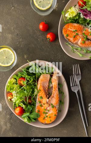 Ein köstliches herzhaftes Mittagessen, ein gebratenes Stück Forellensteak und eine Mischung aus verschiedenen Arten von Grünsalat, Abendessen mit gesundem rotem Fisch Stockfoto
