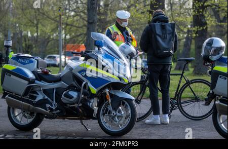 Leipzig, Deutschland. Mai 2021. Ein Polizeibeamter der Leipziger Verkehrspolizei überprüft einen Radfahrer in der Jahnallee in Leipzig. Die Kontrollen führt die Leipziger Polizei im Rahmen der bundesübergreifenden Verkehrssicherheitskampagne sicher.mobil.leben durch. Ziel ist es, die Straßenverkehrssicherheit für alle Verkehrsträger zu erhöhen, die am Straßenverkehr beteiligt sind. Quelle: Hendrik Schmidt/dpa-Zentralbild/ZB/dpa/Alamy Live News Stockfoto