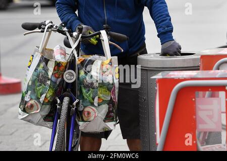 München, Deutschland. Mai 2021. Öffentliches Leben in Zeiten der Coronavirus-Pandemie in München. Ein Flaschensammler sucht in einem Mülleimer nach Mehrwegflaschen. An seinem Fahrrad hängen Plastikkoffer aus einem Discounter mit leeren Flaschen und Getränkedosen. Credit: dpa/Alamy Live News Stockfoto