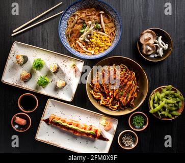 Tisch mit typisch japanischem Sushi, Lachs-Tataki, Miso-Suppe, knusprigen Hühnernudeln, Edamame. Von oben gesehen. Stockfoto