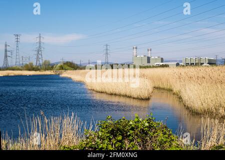 Ein Pool und Schilf auf der Caldicot-Ebene im Newport Wetlands National Nature Reserve mit dem Kraftwerk Uskmouth. Nash, Newport, Gwent, Wales, Großbritannien Stockfoto