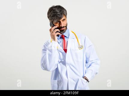 Halbkörperportrait eines gutaussehenden Arztes mit Mobiltelefon auf weißem Hintergrund. Stockfoto
