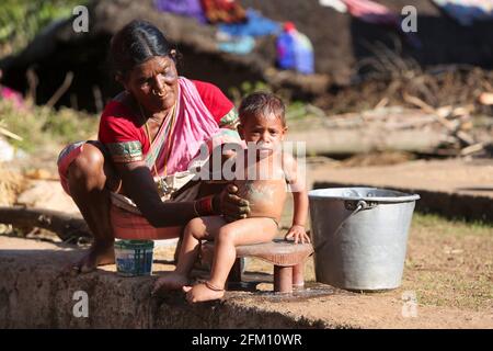 Valmiki-Stammesfrau, die im Dorf Madagada, Andhra Pradesh, Indien, dem Baby ein Bad gab Stockfoto