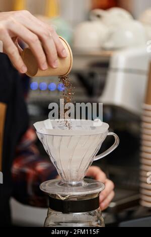 Männliche Hände gießen gemahlenen Kaffee in den Filter. Stockfoto
