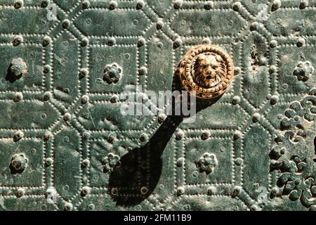 Schöne und Vintage Türgriff löwenförmig auf grünem Metall Tür mit Zierleisten und Balustern Stockfoto
