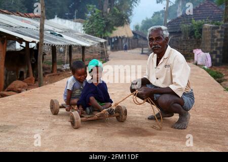 Stammes alter Mann mit Kindern sitzen Kinder auf einem Holzkarren im Dorf Hattaguda, Andhra Pradesh, Indien. BHATKA-STAMM Stockfoto