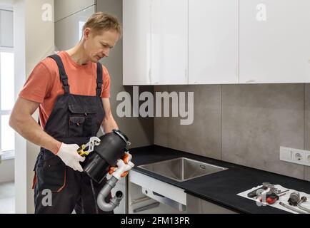 Der Arbeiter installiert einen Hausmüllzerkleinerer für das Spülbecken. Stockfoto