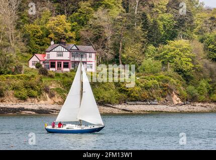 Currabinny, Cork, Irland. Mai 2021. Die Yacht Cuilin fährt unter Segeltuch von Crosshaven aus zu einem Segeltörn, vorbei an dem Holzhaus, das ursprünglich für die internationale Ausstellung von Cork im Jahr 1902 gebaut und schließlich in Curabinny, Co. Cork, Irland, wieder zusammengebaut wurde. - Credit; David Creedon / Alamy Live News Stockfoto