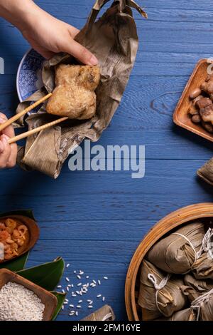 Zongzi Reisknödel mit Zutaten Draufsicht für chinesisches traditionelles Drachenboot Festival (Duanwu Festival) über blauem Holztisch Hintergrund. Stockfoto