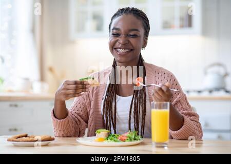 Beginn Des Tages. Glückliche Schwarze Frau Beim Frühstück In Der Küche Stockfoto