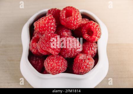 Frische Himbeeren in einer kleinen weißen Schüssel. Stockfoto