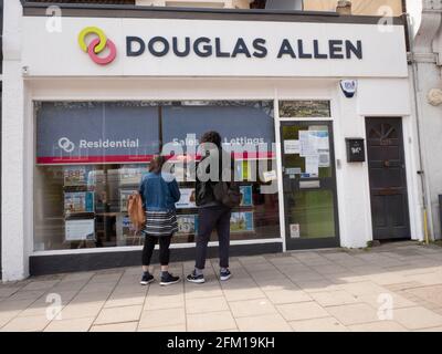 Douglas Allen, Londoner Immobilienmakler und Immobiliendienstleistungsgeschäft, North East London, Großbritannien, mit einem Paar, das im Fenster schaut Stockfoto