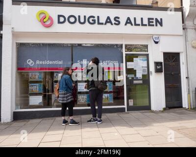 Douglas Allen, Londoner Immobilienmakler und Immobiliendienstleistungsgeschäft, North East London, Großbritannien, mit einem Paar, das im Fenster schaut Stockfoto