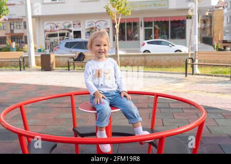 Niedliches kleines kaukasisches Kind, das auf einer Schaukel auf dem Spielplatz reitet. Stockfoto