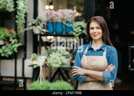 Selbstbewusster Besitzer eines kleinen Unternehmens, Kellner eines Öko-Cafés und Blumenhändler warten auf Kunden Stockfoto