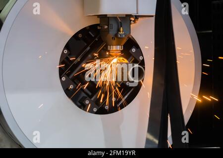 Laserschneidmaschine arbeitet mit zylindrischem Metallwerkstück mit Funken Stockfoto