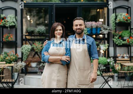 Besitzer von Geschäften und Blumenstudios, Kellner im Öko-Café und Begrüßung der Gäste im Freien Stockfoto