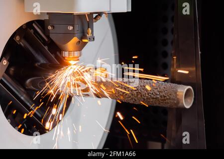 Laserschneidmaschine arbeitet mit zylindrischem Metallwerkstück mit Funken Stockfoto