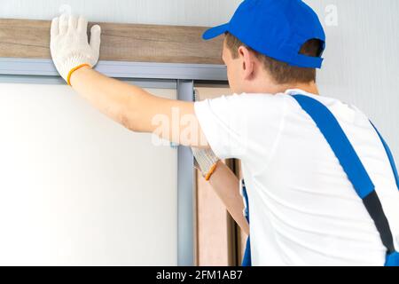 Die Werkstatt in Overalls installiert eine Schiebetür, Nahaufnahme Stockfoto