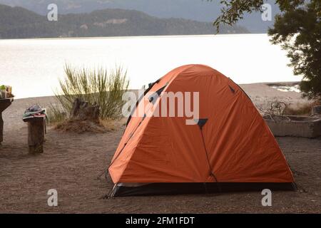 Zelt auf einem Campingplatz aufschlagen. Camp mit Naranga-Zelt am Ufer eines Sees. Berge im Hintergrund Stockfoto