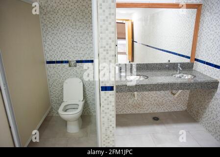 Modernes prívate Schulbad, mit neuen Fliesen, Waschbecken, Toilettenpapier. Stockfoto