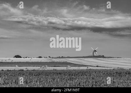 Graustufenaufnahme einer Windmühle auf einem Farmfeld in der Normandie, Frankreich Stockfoto