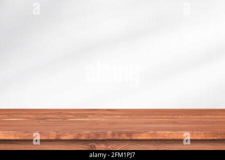 Langer Holztisch vor der Wand mit sanftem Licht. Leerer Schreibtisch, Regal oder Tischplatte für Schablone. Stockfoto