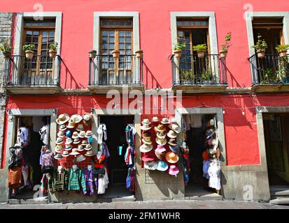 Kolonialgeschäft mit symmetrischen Fenstern, handgefertigten Eisenbalkongeländern und bunten Hüten und Souvenirs in Guanajuato, Mexiko. Stockfoto