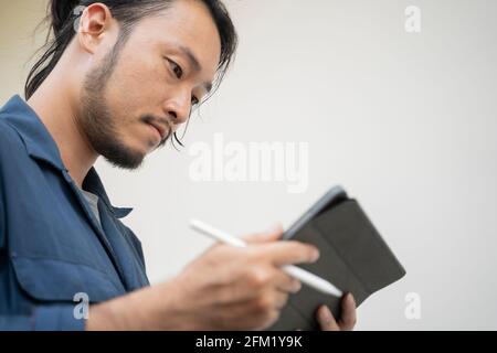 Ein Mechaniker mit einem Tablet, um es herauszufinden. Stockfoto