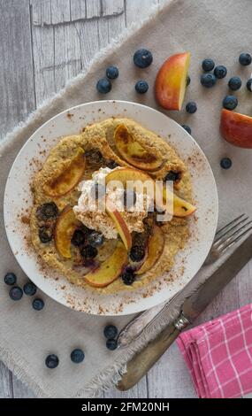 Lecker frisch gebackene glutenfreie Haferflocken Pfannkuchen mit Äpfeln gebacken Und Heidelbeeren und gekrönt mit proteinreichem Quark und Zimt Stockfoto