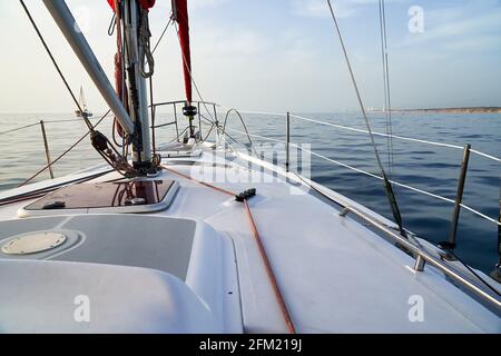 Seitenansicht der Yacht, die im blauen Meer segelt, mit Land von der rechten Seite aus sichtbar. Stockfoto