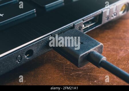 Schwarzes USB-Kabel an den USB-Anschluss EINES ANGESCHLOSSEN Schwarzes Notebook Stockfoto