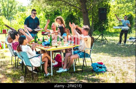 Fröhliche Freunde, die gemeinsam Spaß auf der Grill-PIC-Party haben - Jugendliche aus verschiedenen Rassen beim Open-Air-Food-Festival - Jugendfreundschaftskonzept Stockfoto