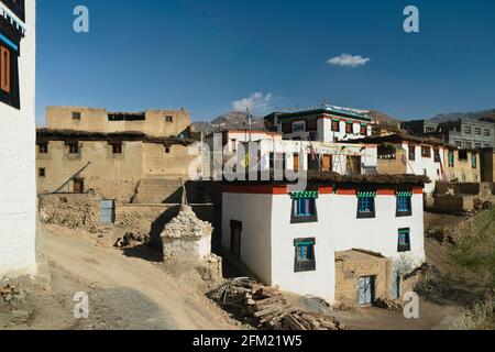 Traditionelle Dorfhäuser mit Flachdächern und buddhistischen Gebetsfahnen, flankiert vom Himalaya unter blauem Himmel in Kibber, Himachal Pradesh, Indien. Stockfoto