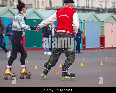 Menschen, die in Brighton Rollerskaten fahren, halten sich die Hände Stockfoto