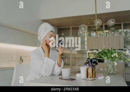 Glückliche, gesunde Frau im Bademantel, die sich um ihre Haut kümmert Nach dem Duschen oder Baden zu Hause Stockfoto