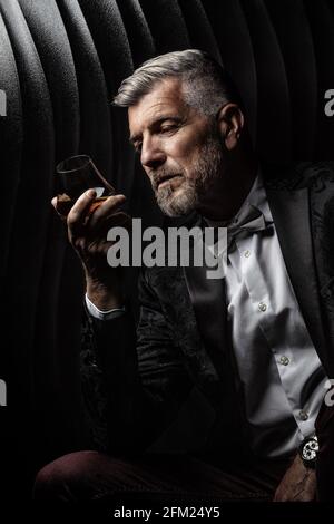 Porträt eines Gentleman, der sein Glas Alkohol beobachtet Stockfoto