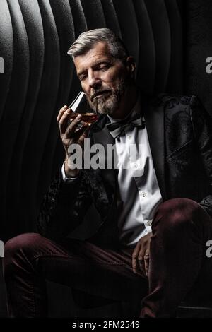 Porträt eines Gentleman, der sein Glas Alkohol beobachtet Stockfoto