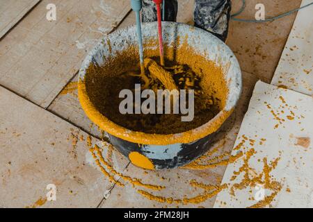 Foto in Bewegung mit einem Arbeiter, der farbigen Polyurethanmörtel mischt Mit Epoxidharz Stockfoto