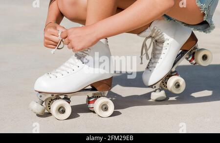 Nahaufnahme der Hände des Skaters, die die Schnürsenkel eines binden Rollschuh Stockfoto