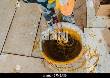 Foto in Bewegung mit einem Arbeiter, der farbigen Polyurethanmörtel mischt Mit Epoxidharz Stockfoto