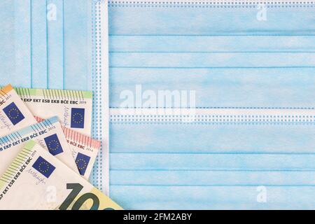 Euro-Banknoten auf Einweg-Schutz medizinische Gesichtsmasken Hintergrund. Draufsicht Stockfoto